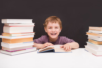preschooler little boy with books on a black background of a slate board