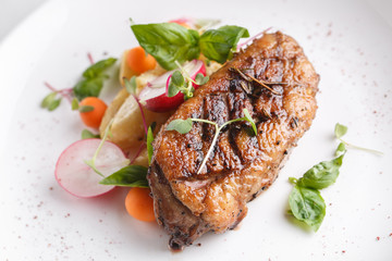 Roast duck breast with vegetables. Served on a white plate