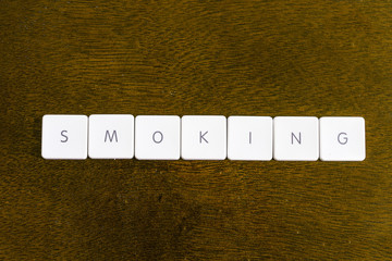 SMOKING word written on plastic keyboard alphabet with dark background