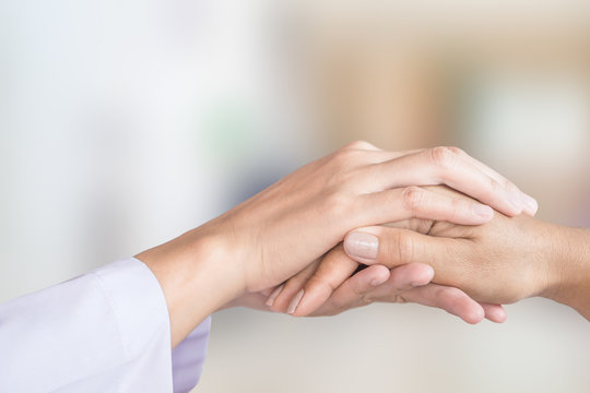 female doctor hand comforting patient with blur background of hospital room