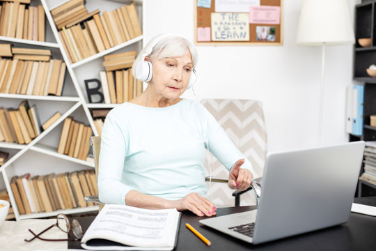 Employer and freelancer. Appealing senior freelancer using laptop while wearing headphones