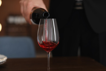Man pouring wine into glass on table