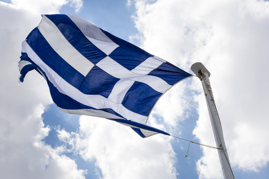 waving Greek flag against the blue sky with clouds - Powered by Adobe