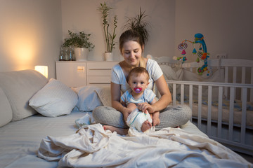 Young mother changing diaper to her baby boy before going to bed