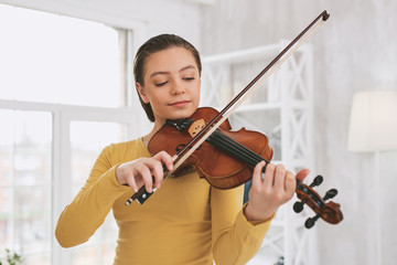 Be attentive. Pretty brunette bowing head while looking at her instrument