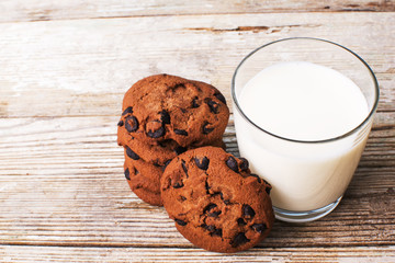 chocolate chip cookies and a glass of milk on an old board, top view