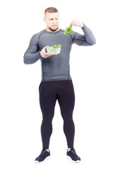 Fototapeta na wymiar Full-length portrait of well-muscled male athlete holding lunch box with fresh celery