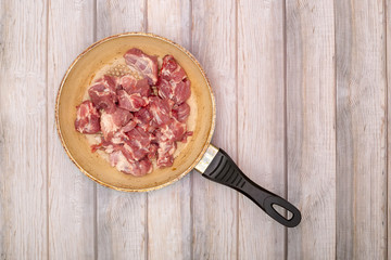 Chopped fresh meat in a frying pan on wooden planks