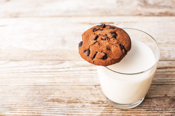 chocolate chip cookies and a glass of milk on an old board, top view