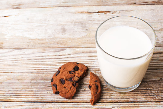 chocolate chip cookies and a glass of milk on an old board, top view