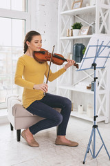 Setup strings. Cheerful brunette keeping smile on face while playing the violin © Viacheslav Yakobchuk