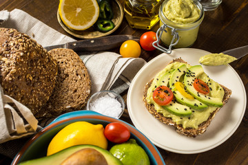 Fresh Avocado Spread Guacamole and Slices with Cherry Tomato and Black Sesame on a Piece of Bread. Healthy Breakfast Concept.