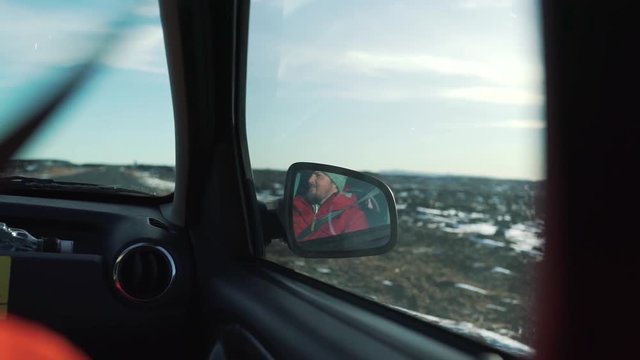 a reflection of a travel man in a car mirror.