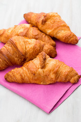 Tasty buttery croissants on old wooden table.