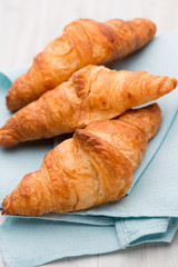 Tasty buttery croissants on old wooden table.