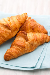 Tasty buttery croissants on old wooden table.