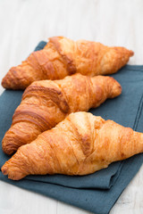 Tasty buttery croissants on old wooden table.