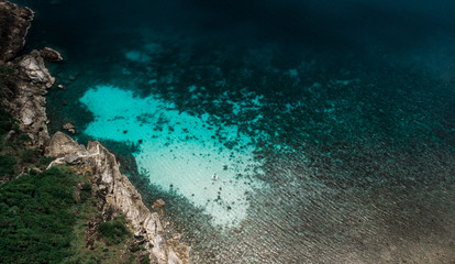 Aerial view of sailing boat next to reef in blue lagoon. Bird eye view