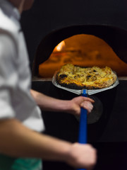 chef removing hot pizza from stove
