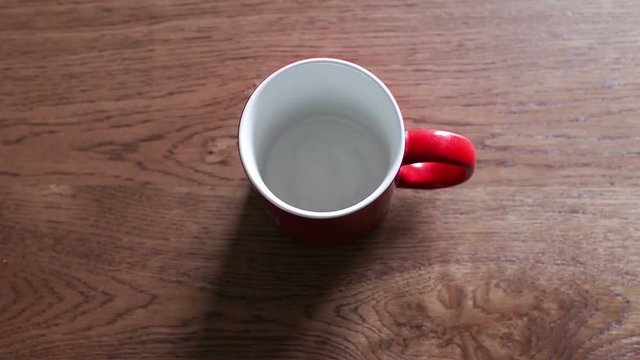 A red cup on a black table is filled with coffee. Cup filled with coffee, breakfast and work break. Coffee break with a red mug. Coffee refilling