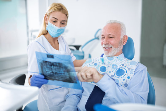 Dentist With Sterile Mask And Dental Instruments Held Exam Teeth Of Patient