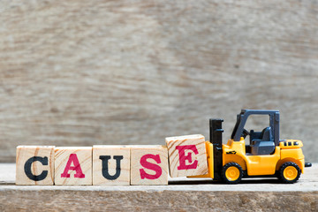 Toy forklift hold letter block e to complete word cause on wood background