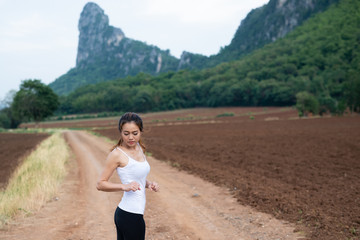 Asian female runners are stretching muscles before exercise. jogging on mountain road. The concept of health and fitness