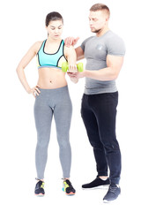 Gym trainer assisting fit young woman doing dumbbell exercise