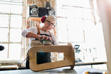 Senior woman doing woodwork in a workshop
