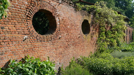 Old brick wall in a public garden with plants.