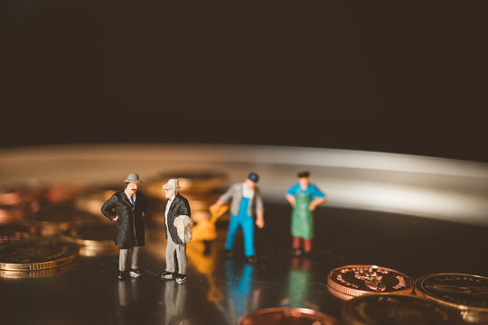 Miniature people, couple boss talking with worker lifting stack coins background using as business and financial concept