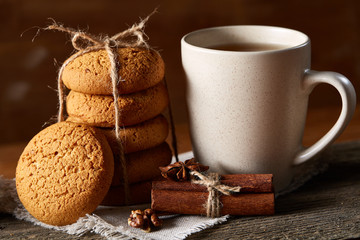 Traditional Christmas tea concept with a cup of hot tea, cookies and decorations on a wooden table, selective focus