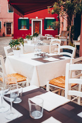 Fototapeta na wymiar Table setting in Italian restourant, terrace. Wine glass, tablecloth