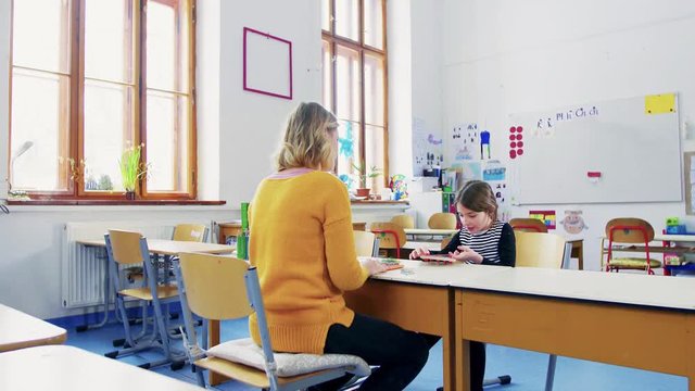 A small girl with teacher learning at school.