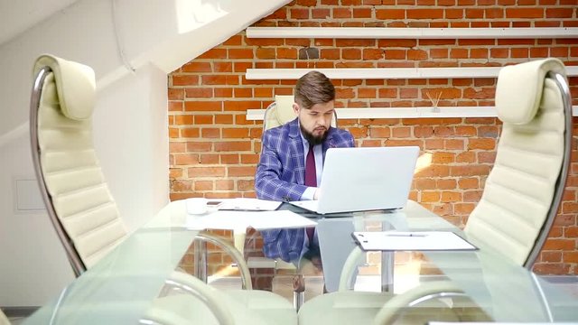 a rich man works for a laptop in his office, a gentleman is a businessman of a modern firm