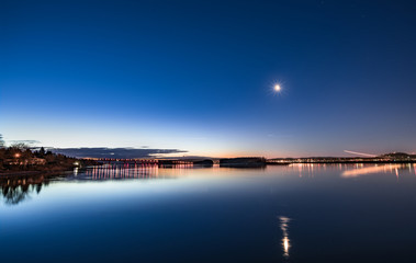 Dawn on a calm river with moon and air traffic