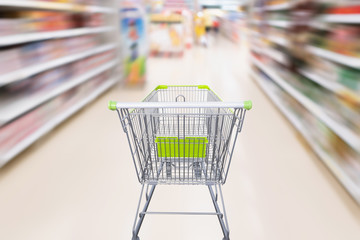 shopping cart with abstract motion blur supermarket discount store aisle and product shelves interior defocused background