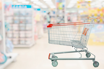 Shopping cart with abstract blur supermarket aisle interior background with baby formula milk product and clothing on shelves