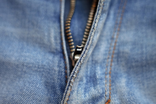 macro texture of worn blue denim with metal zipper on jeans