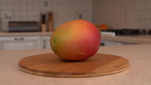 Close up of fresh mango fruit. Rotating camera with white kitchen on the background. Dolly-shot.