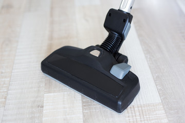 close up of vacuum cleaner over wooden floor