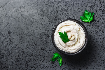 Summer garden whipped white bean dip on dark concrete background. Top view, space for text. 