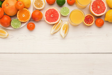 Platter of assorted citrus fruits on white wooden planks, top view