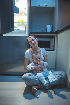 Sleepy Tired Woman Sitting Kitchen Floor At Night And Feeding Her Baby Boy With Milk