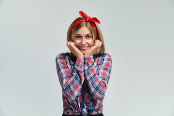Studio portrait of a young woman in a plaid shirt and a bow on her head. Positive joyful cheerful emotions