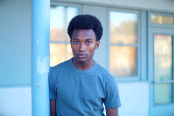 young man outside orange sunlight windows urban concrete pole city