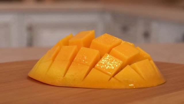 Close up of sliced mango fruit. Rotating camera with white kitchen on the background. Dolly-shot.