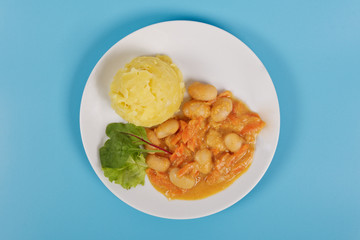 Beans with carrots and potatoes on a blue background
