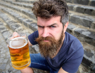 Hipster on strict face drinking beer outdoor, raising drink up. Cheers concept. Man with beard and...