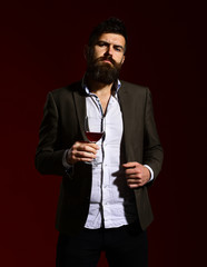 Man in suit toasting with sparkling glass of red wine
